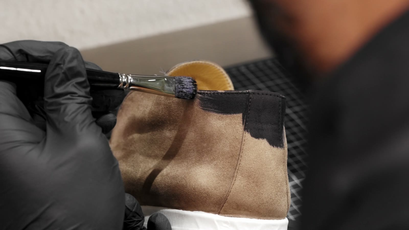 A suede boot being brushed by hand at the FRSHR bench