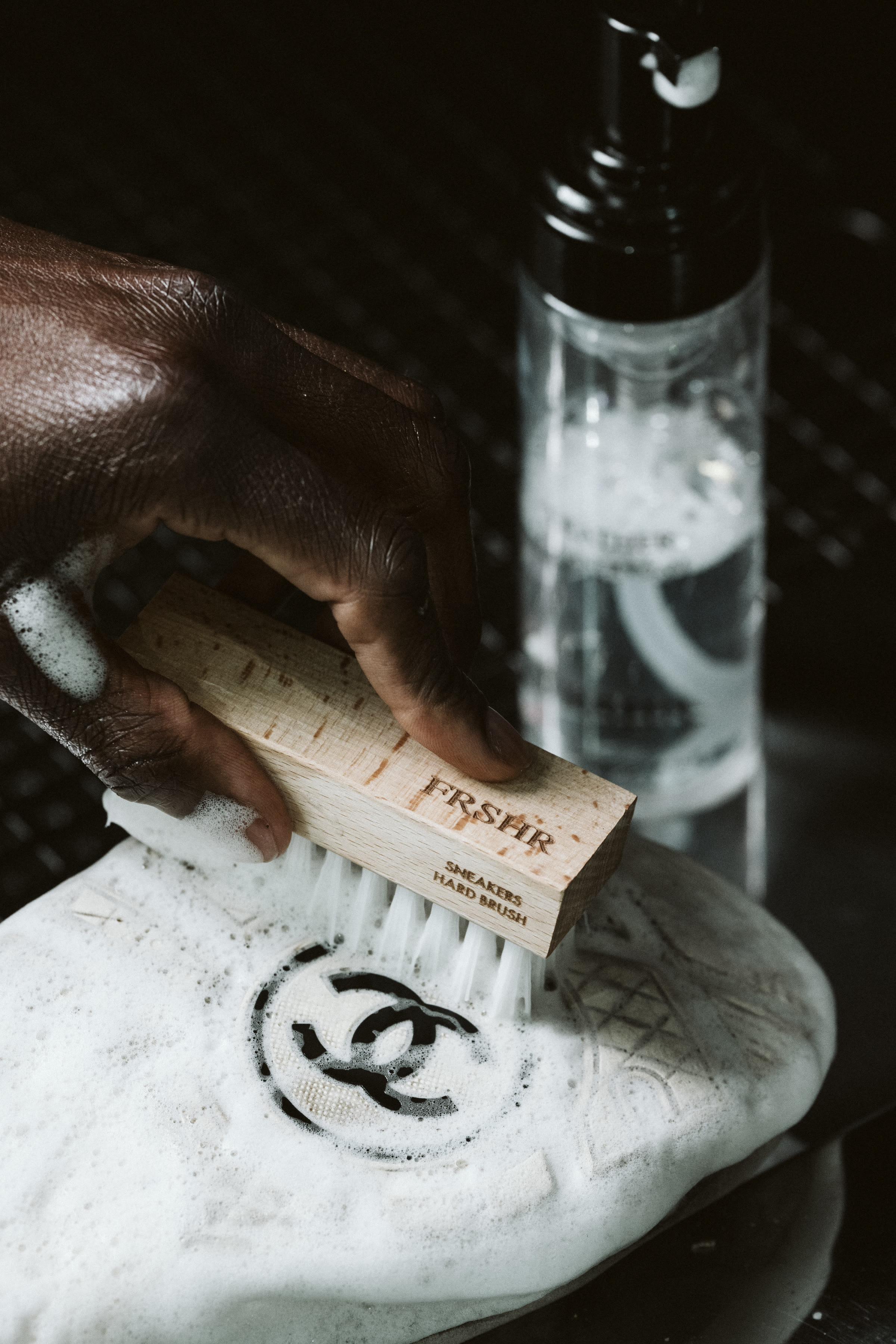 A Chanel sneaker being cleaned by hand with foam and a FRSHR brush